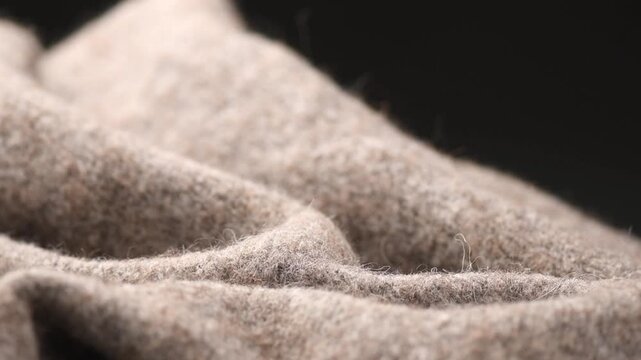 Knitted Wool over black background. Real Natural beige color craft wool mohair clothes texture closeup. Cashmere Soft and fluffy merino wool macro shot. Woolen fabric backdrop. Rotating border. 