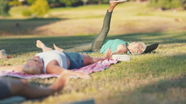 Senior women exercising lying on grass during yoga class