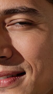 Vertical video: Smiling man opening left eye and shifting gaze to camera as focus changes in studio