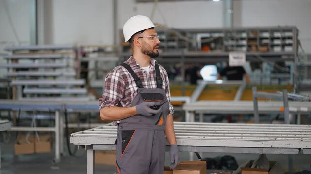 Industrial male worker talking on walkie talkie in factory