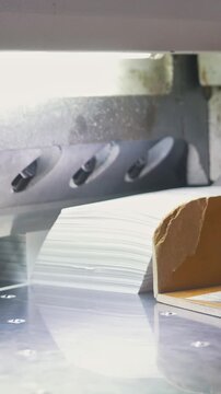 Hands of worker takes away reams of paper from cutting maschine