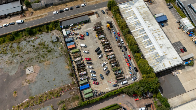 Aerial view of Stevenage Recycling Centre with cars parked in bays and rows of large waste containers at an industrial facility in Stevenage, England, United Kingdom.