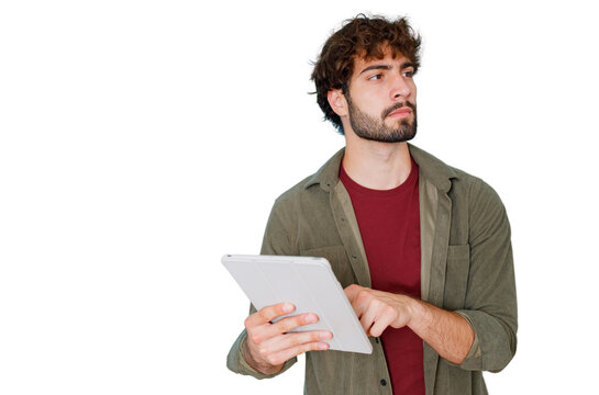 Young man holding tablet and looking away, pondering new ideas for business, future planning, and digital research