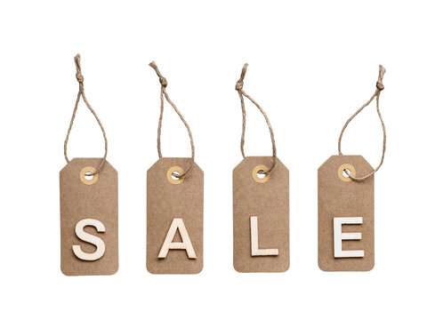 Four brown kraft paper tags hanging by twine with white wooden letters spelling SALE isolated on white background
