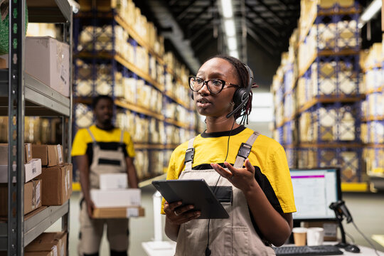 A female warehouse worker answers client calls on a headset in a depot, handling problems and delays via a customer service helpline; a call center clerk troubleshoots shipment issues.