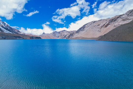Aerial view of the turquoise waters of Tilicho Lake surrounded by the rugged, snow-dusted peaks of the Himalayas in Nepal.