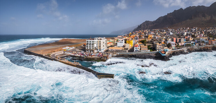 Aerial view of Ponta do Sol on Santo Antao, featuring colorful buildings, a breakwater, and waves crashing against the shore in Ponta do Sol, Ribeira Grande, Cabo Verde.