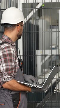 Technician performing maintenance checks on electrical cabinet using laptop