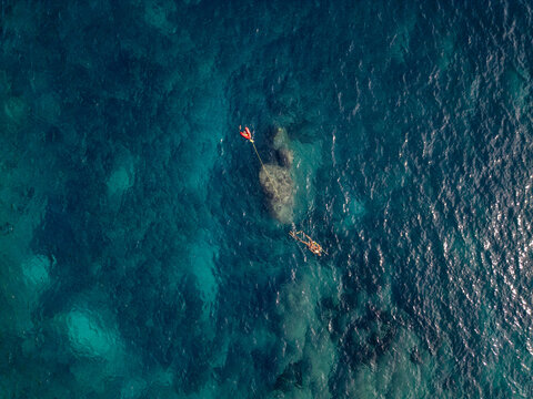 Aerial view of a snorkeler swimming in the clear turquoise waters of Cala Llebeig with a bright orange buoy, El Poble Nou de Benitatxell, Valencian Community, Spain.