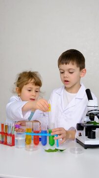 Laboratory examination of a child with test tubes, reagents and a microscope. Selective focus.