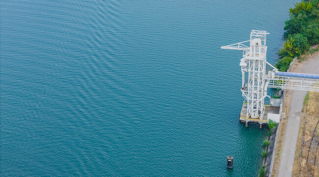 Aerial view of an industrial bulk loading tower with an enclosed conveyor system on the Rhone River in Le Pouzin, Auvergne-Rhone-Alpes, France.