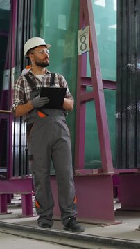 Industrial worker inspecting glass sheets in factory warehouse