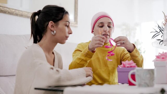 Mother with cancer and daughter sharing a loving moment while wrapping gifts