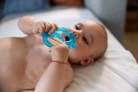 Close up of baby chewing soft silicone teether at home.