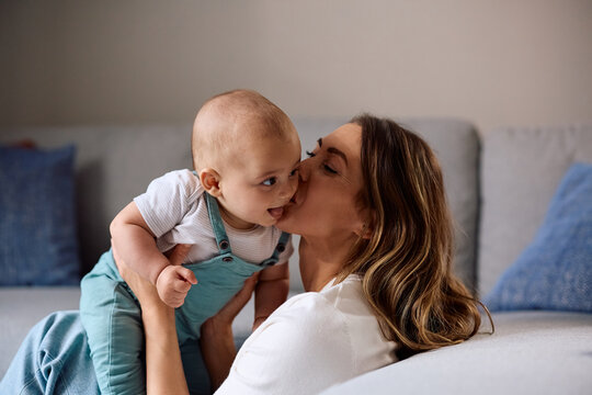 Joyful mother kissing her baby son at home.