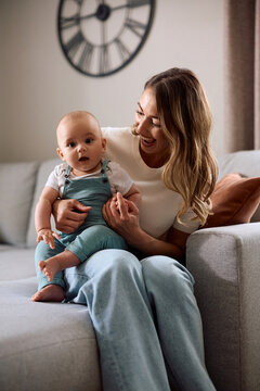 Happy single mother with her baby son relaxing in living room.