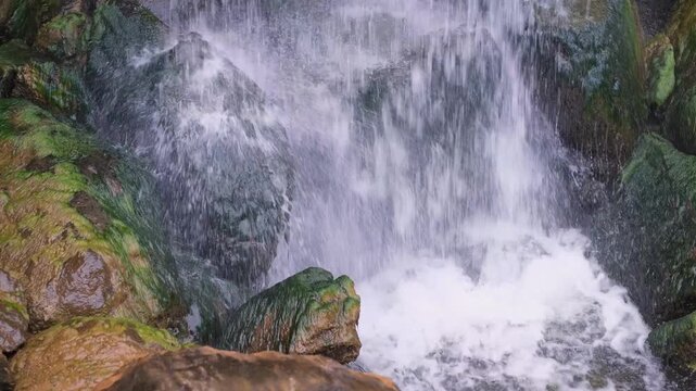 Powerful water flowing over mossy rocks at waterfall