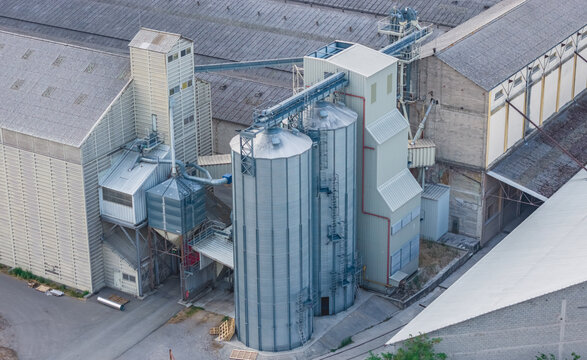 Aerial view of grain silos connected by conveyor systems at an agricultural storage and processing facility in Le Pouzin, Auvergne-Rhone-Alpes, France.