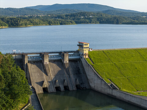 Aerial view of the Dobczyce Dam with its concrete structure, control tower, and grassy embankment overlooking the reservoir, Dobczyce, Lesser Poland, Poland.