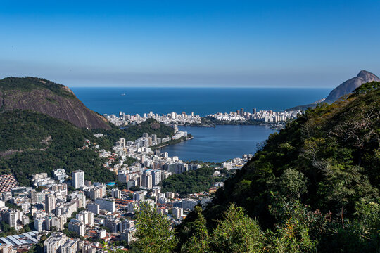 The Rodrigo de Freitas Lagoon emerges amidst the hills, featuring calm waters, surrounding vegetation, and a city shaped by its geography. Rio de Janeiro, Brazil.