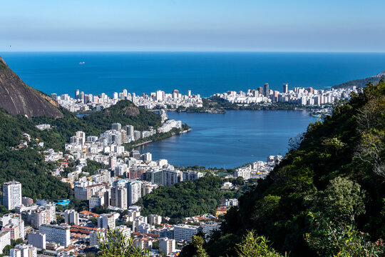 The Rodrigo de Freitas Lagoon emerges amidst the hills, featuring calm waters, surrounding vegetation, and a city shaped by its geography. Rio de Janeiro, Brazil.