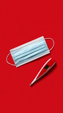Health tools on a red background with a mask and thermometer for hygiene and care Generative AI