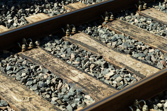 Traverses en bois et rails de chemin de fer avec ballast en pierre sous la lumi&egrave;re du soleil.
