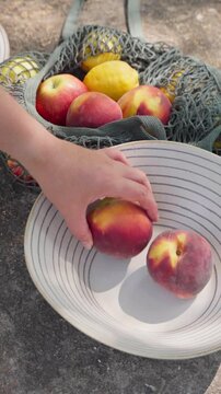 Placing Fresh Peaches in a Bowl from a Market Bag