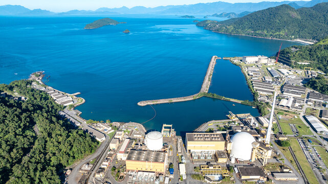 Aerial view of the Nuclear Power Plant Angra 2 with its white containment domes, industrial buildings, and tall chimney situated along the coastline of Angra dos Reis, Rio de Janeiro, Brazil.