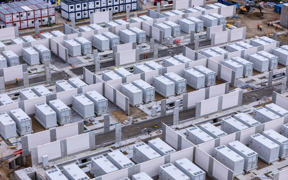Aerial view of the Zarnowiec Energy Storage facility featuring rows of white battery containers separated by concrete walls at a construction site in Wejherowo County, Pomeranian Voivodeship, Poland.
