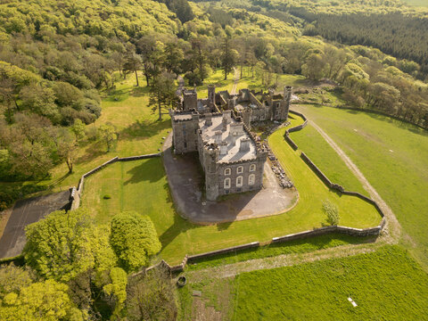 Aerial view of Castlefreke Castle surrounded by lush green fields, stone walls, and dense woodland in Castlefreke, County Cork, Ireland.