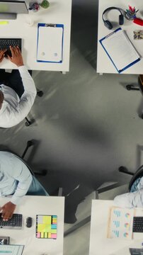 Diverse office colleagues share reports and planning insights in a modern office, using project planning and performance metrics to organize reports, data and team decisions.