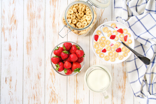 Healthy breakfast with corn rings on a white wooden table, top view.