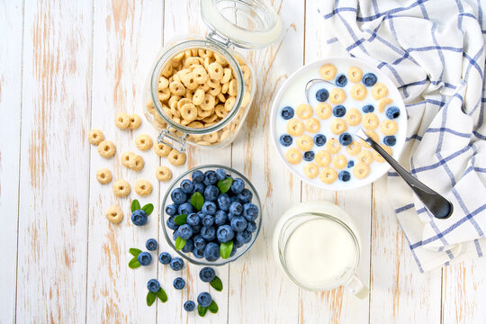 Healthy breakfast with corn rings and  blueberry on a white wooden table, top view.