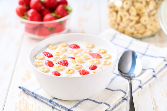 Healthy breakfast for kids with corn rings and strawberry on a light kitchen table, selective focus.