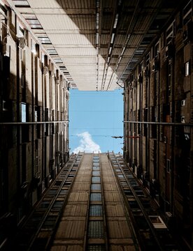 Low angle view looking up at brutalist concrete apartment buildings framing a square piece of blue sky.