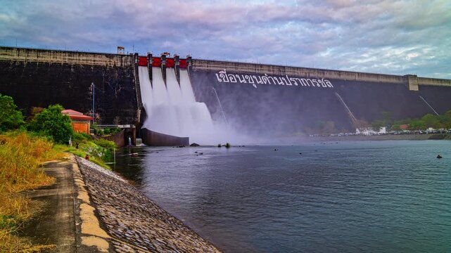 Nakornnayok Thailand,06 December 2025: A dynamic view of the Khun Dan Prakan Chon Dam releasing water through its spillways, showcasing powerful water flow against a dramatic cloudy sky.