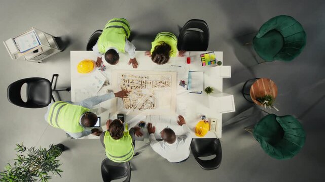 Doctors discuss therapy options from an overhead angle in a healthcare office, using clinical information and treatment notes to support care planning inside a medical team.