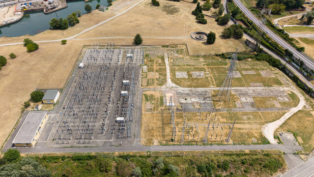 Aerial view of the electrical substation with high-voltage power lines and transformers surrounded by dry fields in Tavazzano con Villavesco, Lombardy, Italy.