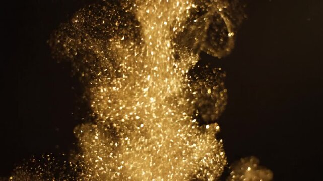 Sparkling golden particles falling on a black background