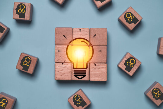 Brainstorming idea concept with glowing light bulb assembled from wooden blocks, symbolizing creative thinking, innovation, problem solving, teamwork, collaboration, strategy, and business success.