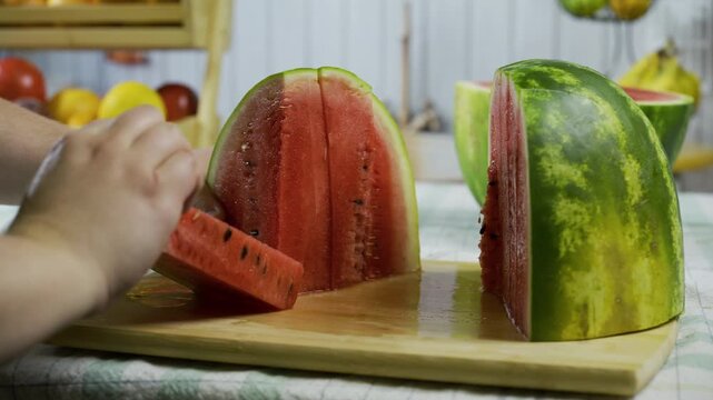 Person in kitchen adjusting slices of watermelon on counter in slow motion