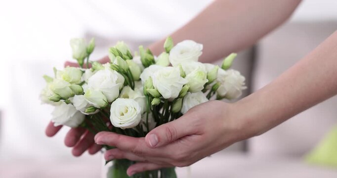 Woman arranging beautiful eustoma flowers in vase indoors, closeup