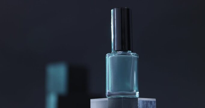 Nail polish in bottle on podium against dark background, closeup. Camera moving right