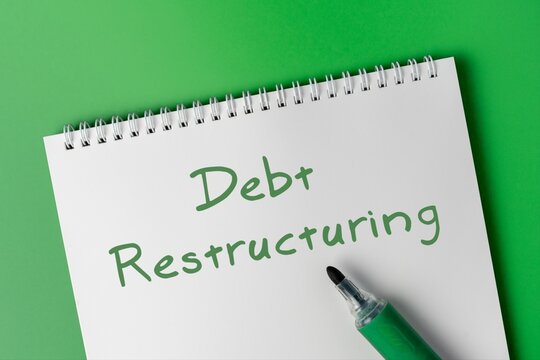 Notebook on a green background with the phrase Debt Restructuring. Financial planning, loan management, economic recovery, bankruptcy solutions concept.