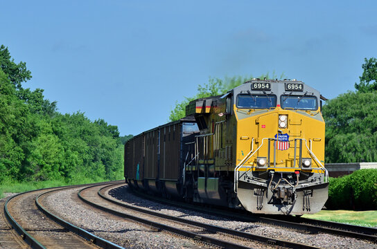 A signle Union Pacific locomotive leads a loaded coal train as it exited a curve into the morning sun at the top of a light grade while passing through a western Chicago suburb.