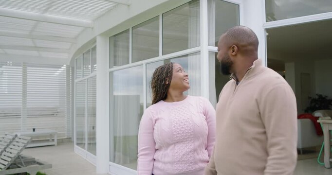 African American couple exiting glass door to patio holding hands raising blue key fob marking move