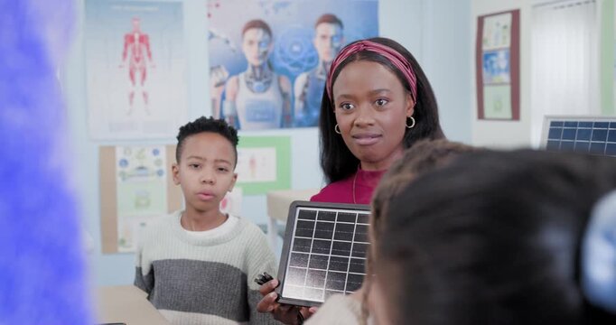 Teacher with youth showing solar panel at table teaching renewables asking boy peers raising hands