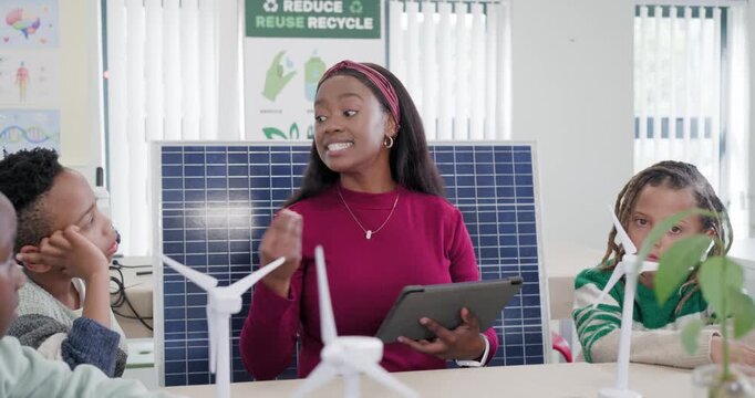 Teacher in classroom using tablet after asking youth raising hands and reaching models about energy