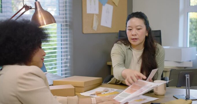 Diverse female team after spreading sketches trading swatches at studio choosing fabric for sample
